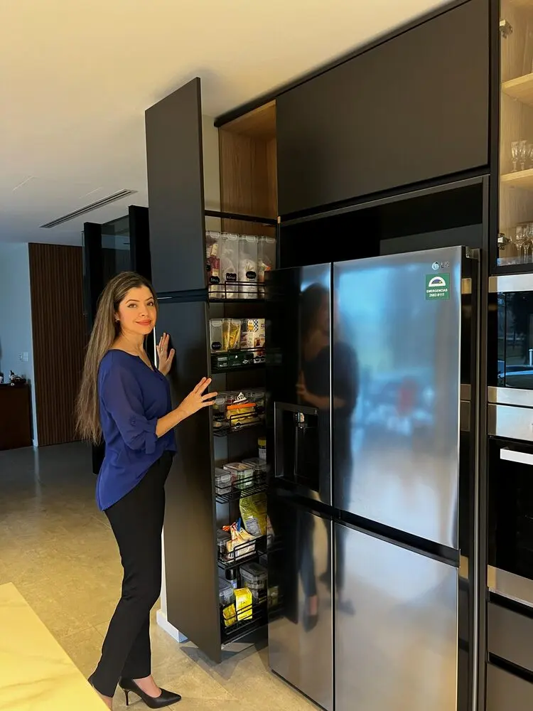 Despensero extraíble abierto junto a la heladera en una cocina negra